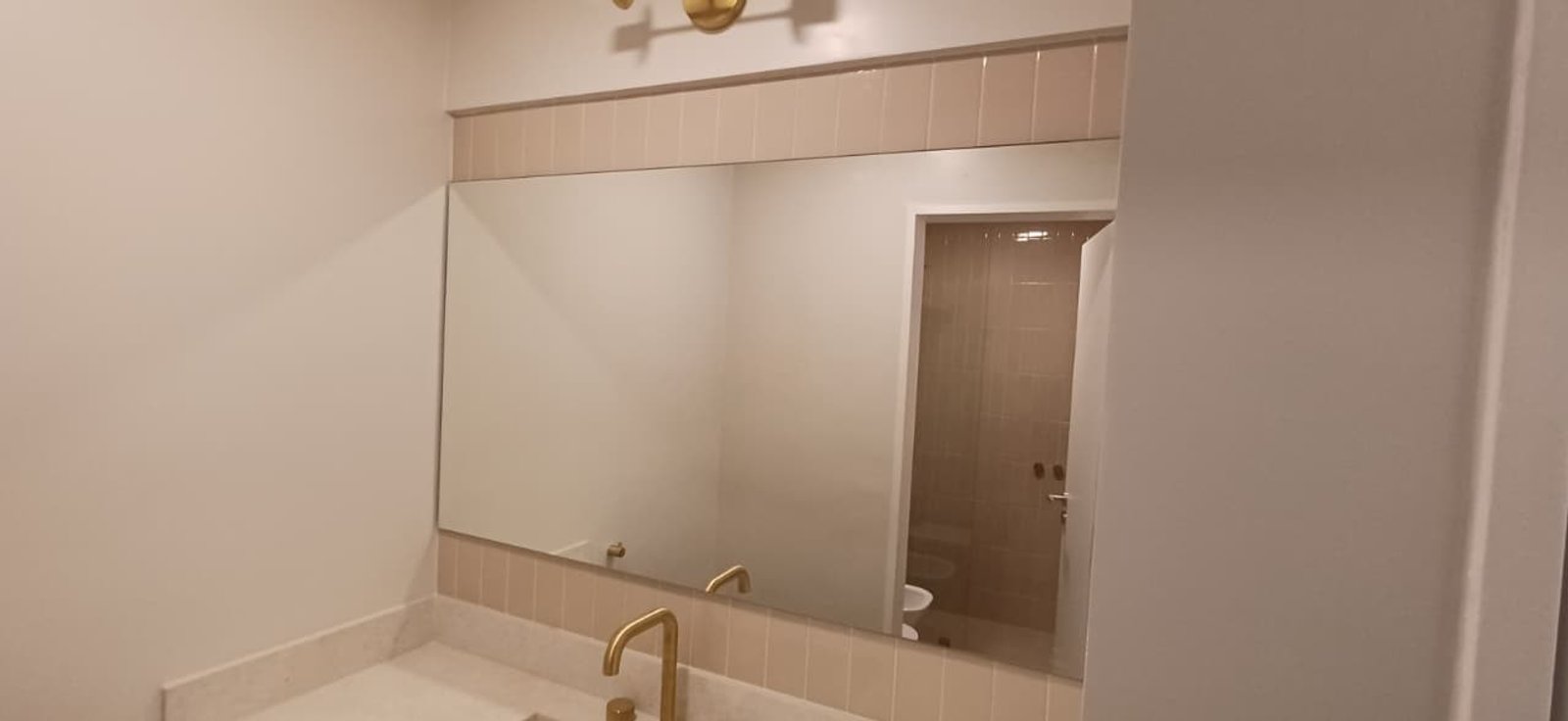 baño moderno con espejo grande y grifería dorada — proyecto Composición de espejos a medida con soportes estructurales — Caballito, por Los Andes Vidrios y Espejos, en Del Barco Ce